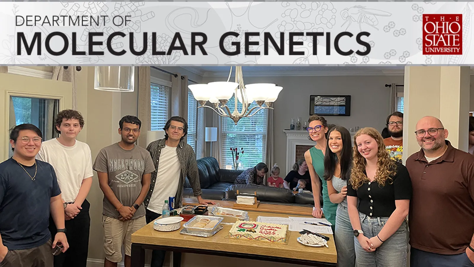 Some of the newest members of the department surround a welcome cake (with adorable DNA decorations on the edges)