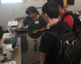 Dr. Amacher showing students larval zebra fish at the Mol Gen Open House