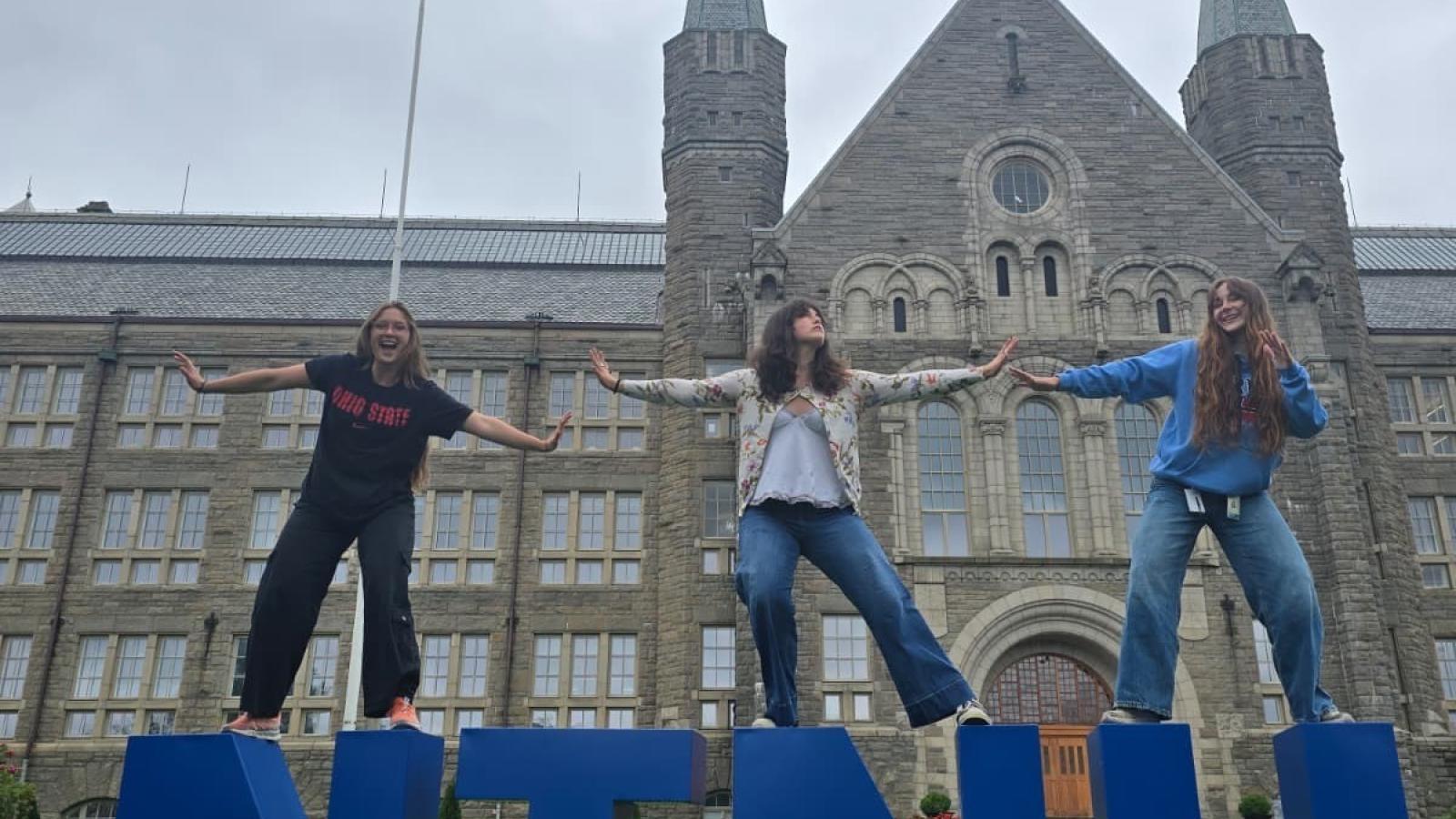 Jillian Philippo (Biomedical Engineering), Grace Whitmore (Entomology) and Abi Singstock (Molecular Genetics) in front of Hovedbygningen (main building) at NTNU during Summer 2025. At NTNU, Grace studied plant adaptation to stress, Abi researched the neural network in zebrafish and Jillian joined a group interested in complex macromolecules as possible biomaterials. 