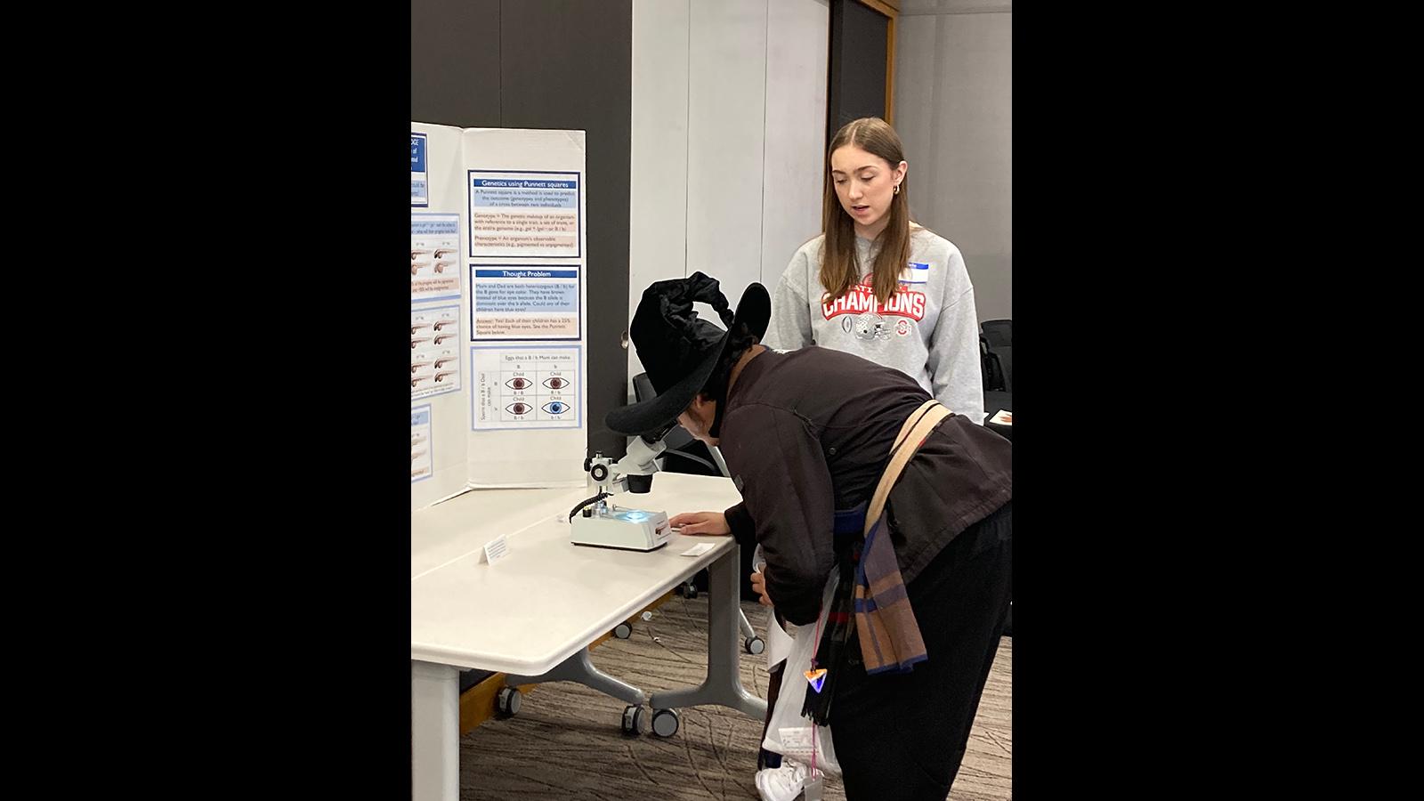 A visitor in costume looks at pigment variants of zebrafish with the help of a volunteer