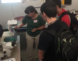 Dr. Amacher showing students larval zebra fish at the Mol Gen Open House